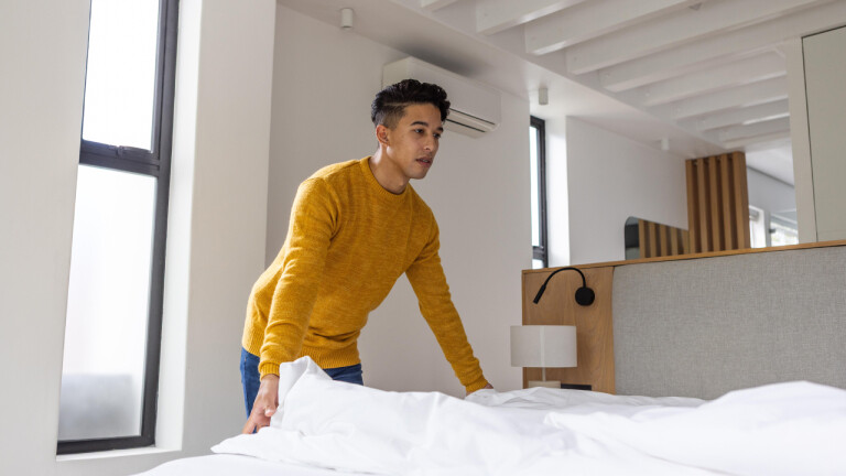 Ein Mann macht sein Bett.