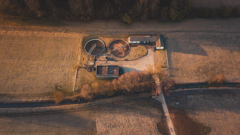 Kläranlage mit runden Becken und Gebäuden inmitten einer weiten Feldlandschaft mit Herbstfärbung, Gechingen, Landkreis Calw, Deutschland