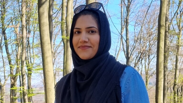 Humaira Waseem blickt in die Kamera, sie steht in einem Wald