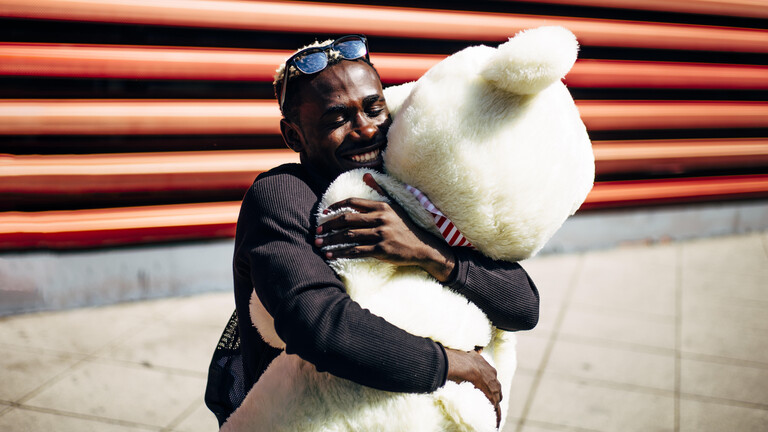 Mann umarmt großen weißen Stoffbären