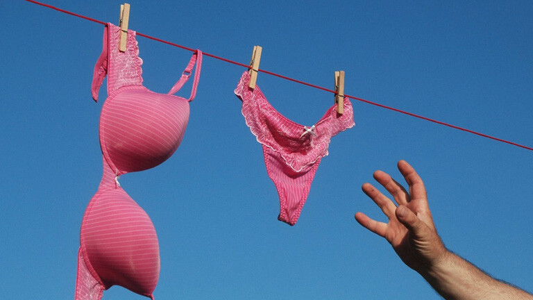 Hand greift nach Slip und BH auf Wäscheleine