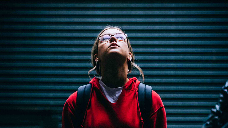 Junge Frau mit Brill schaut in die Luft