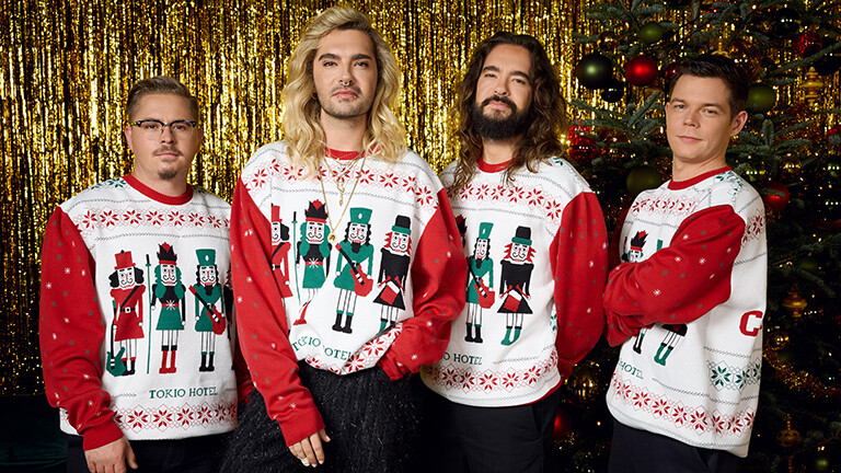 Die vier Mitglieder von Tokio Hotel (von links nach rechts: Gustav Schäfer, Bill Kaulitz, Tom Kaulitz, Georg Listing)posieren in für ihre Single "Your Christmas" selbstdesignten Weihnachtspullis vor goldenem Lametta und geschmücktem Weihnachtsbaum