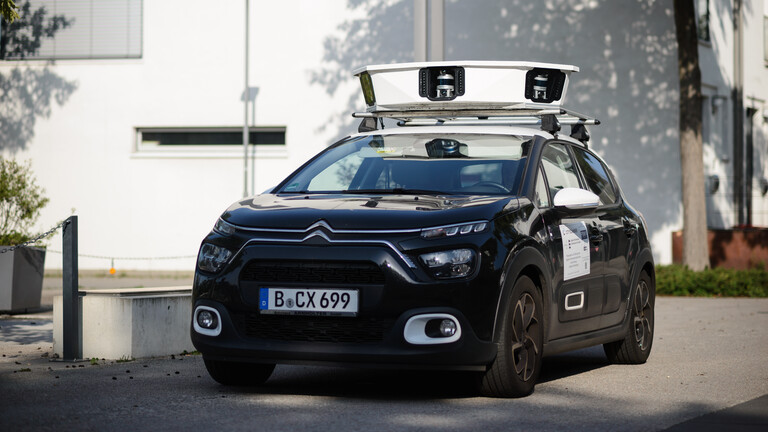 Ein Auto mit einem Scan-Aufsatz steht vor einem Gebäude auf einer Straße