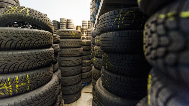 In einer Lagerhalle stapeln sich Autoreifen.
