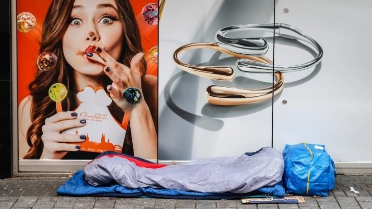 Ein Obdachloser liegt vor einem Geschäft in der Kölner Innenstadt