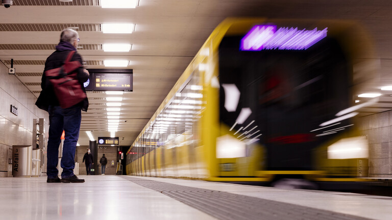 Berliner BVG: Eine Bahn fährt in der Haltestelle ein. Einige Fahrgäste warten bereits an der Haltestelle.