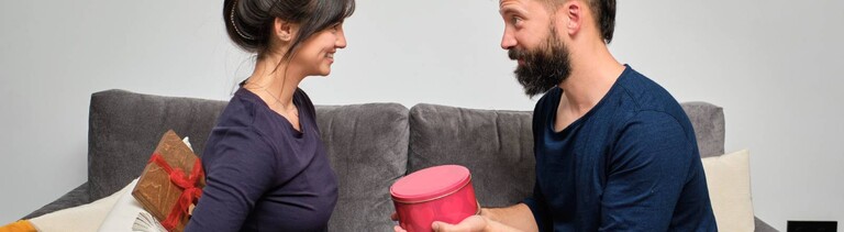 Eine Frau und ein Mann überreichen sich ein Geschenk