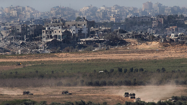 Blick von Israel auf den nördlichen Gazastreifen; im Hintergrund zerstörte Häuser, vorne fahren israelische Militärfahrzeuge (16.11.2023)