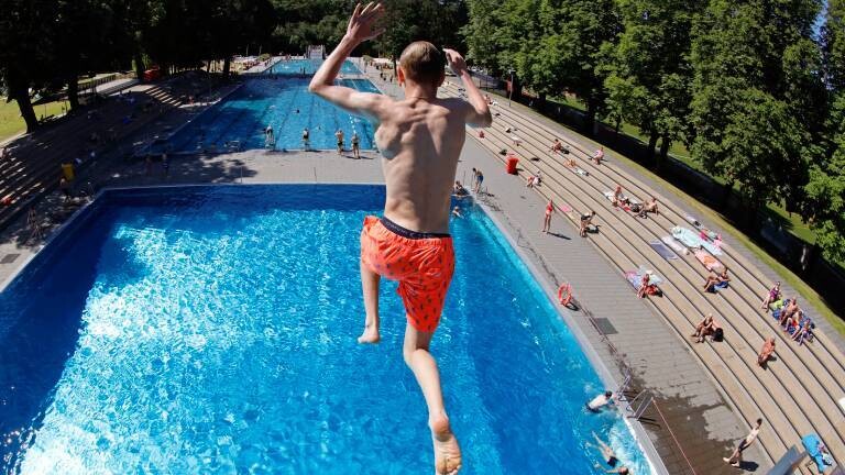 Junge springt im Freibad ins Wasser