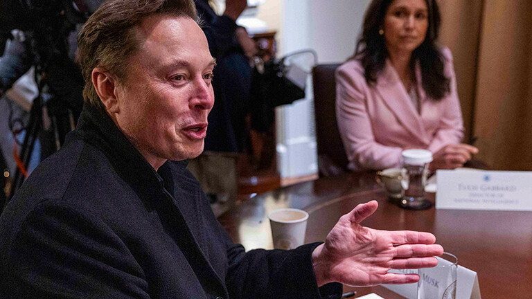 Elon Musk, Chef von Tesla, sitzt bei einer Kabinettssitzung im Weißen Haus an einem Tisch, er lacht und gestikuliert mit den Händen.