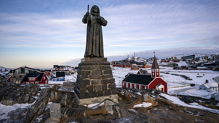 In der grönländischen Stadt Nuuk steht eine Statue des Missionars Hans Egede. Im Hintergrund ist die Stadt zu sehen.