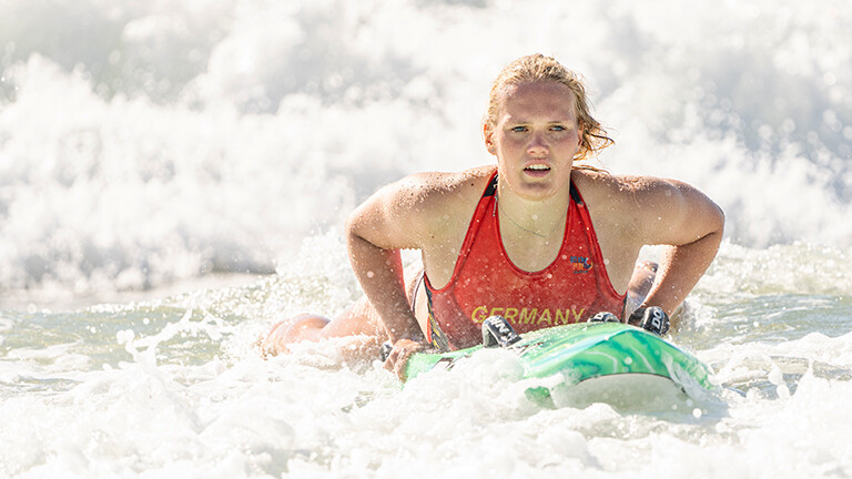Die Sportlerin Lea Kötter bei der WM der Rettungsschwimmer 2024 in Australien. Lea Kötter liegt auf einem Rettungsbrett im Meer und bewegt sich in den Wellen.
