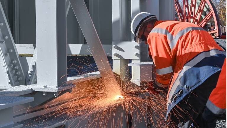 Mann schweißt an einem Gerüst