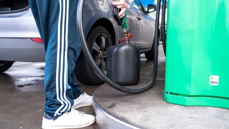 Ein Mann tankt an einer Tankstelle Benzin in einen Kanister.
