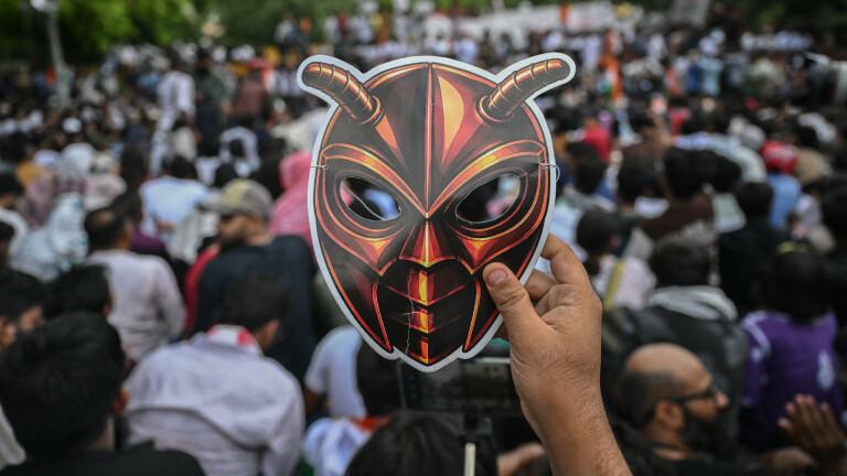 Ein Unterstützer der Cockroach Janta Party (CJP) hält während eines Protests in New Delhi am 6. Juni 2026 eine Maske in Kamera