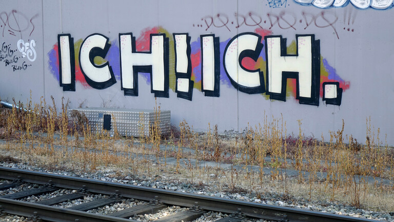 Ich! Ich! steht als Graffiti an einer Wand hinter Bahnschienen.