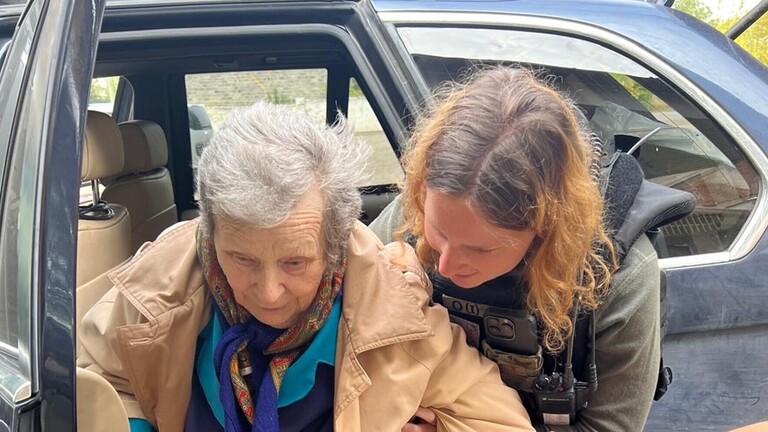 Anna Elsbernd hilft einer Frau mit Gehstock aus einem Auto zu steigen