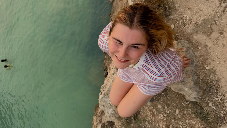 Eine junge Frau namens Nina auf einem Felsen am Meer.