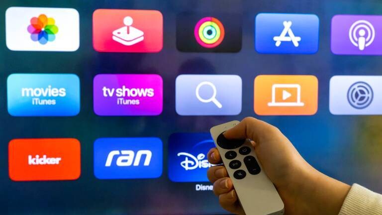 Eine Person steuert mit einer Fernbedienung die Apps (unter anderem ran, Apple, App-Sore, Kicker, Disney Plus) des Smart-TVs.