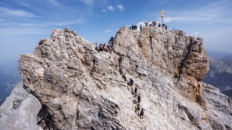 24.08.2023: Zahlreiche Menschen klettern zum Gipfelkreuz der Zugspitze