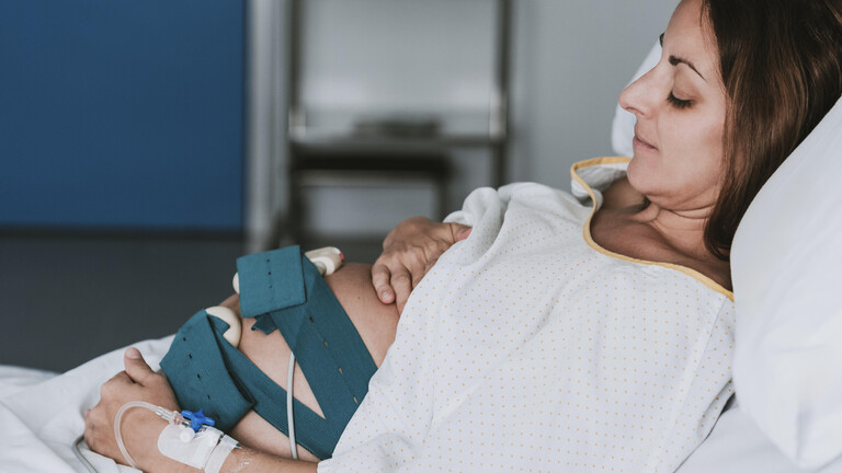 Eine schwangere Frau liegt in einem Krankenhausbett. Sie hat Messgeräte an ihrem Bauch liegen.