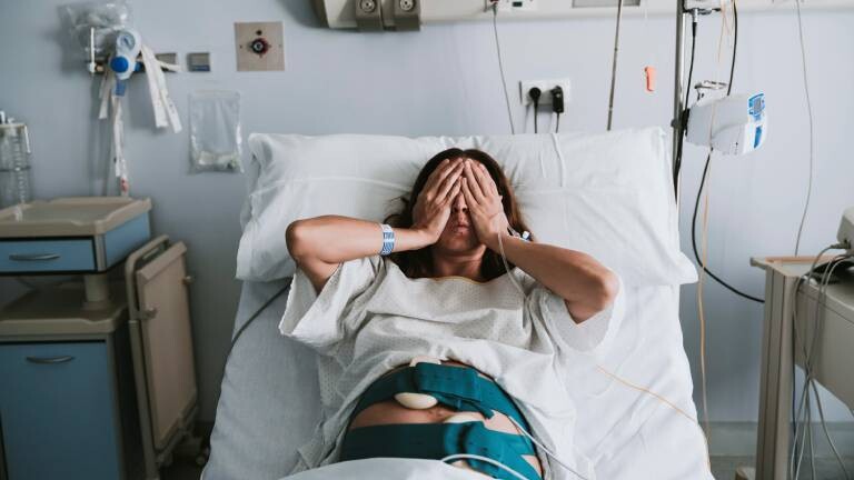 Eine schwangere Frau liegt in einem Krankenhausbett