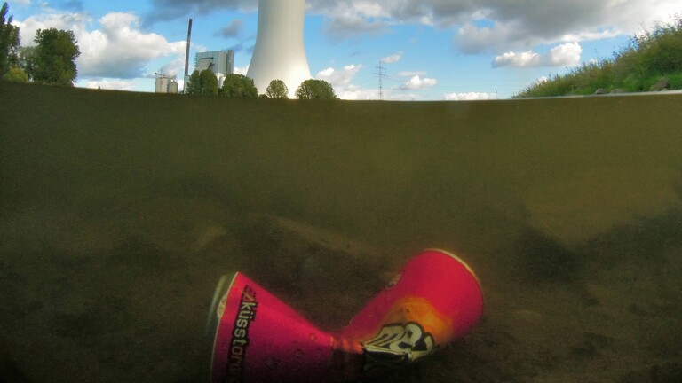 Getränkedose liegt im trüben Rheinwasser