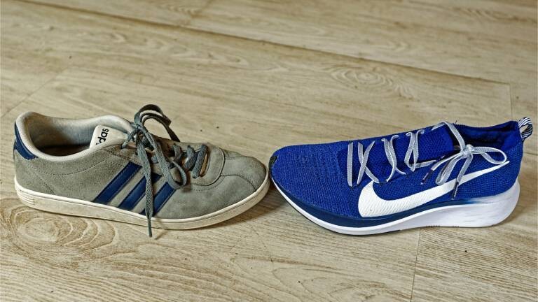 Sportschuhe von Adidas und Nike berühren sich an der Schuhspitze