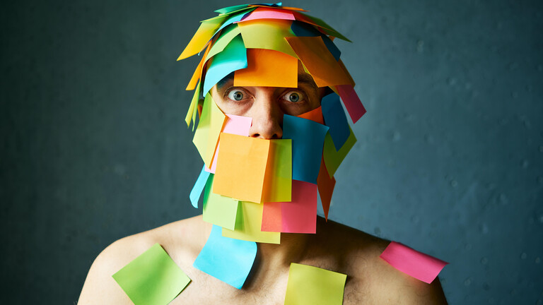 Ein Mann mit vielen bunten Post-its im Gesicht