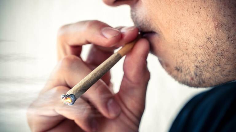 Person kifft einen Joint aus Cannabis bzw. THC in der Öffentlichkeit.