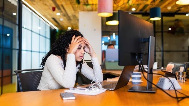 Eine Frau im Büro schaut erschöpft auf einen PC