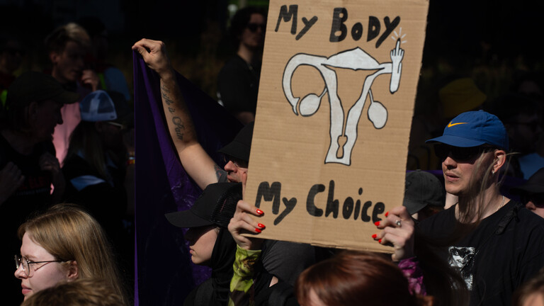 Frau hält Schild mit Gebärmutter unter "My Body, My Choice" in die Höhe (Köln, 21.09.2024)