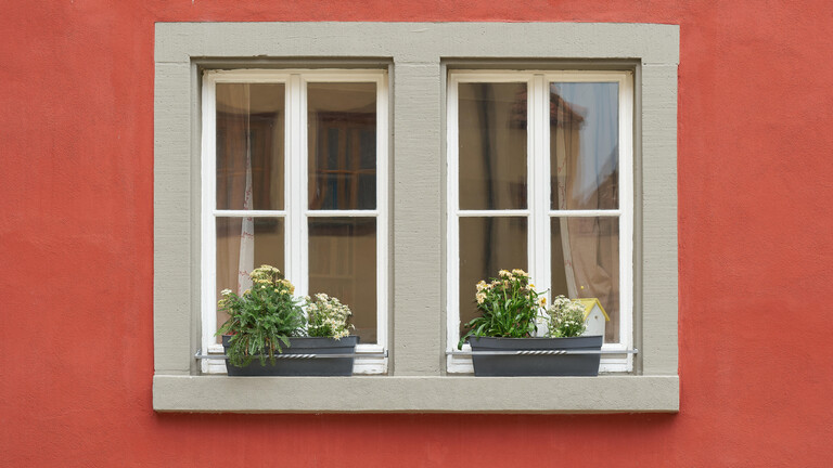 Fenster eines roten Hauses mit Blumen auf dem Fensterbrett
