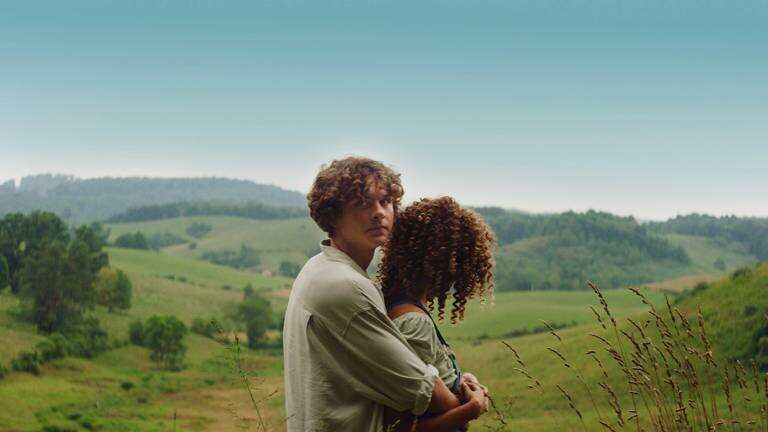 Mann umarmt Frau vor Naturkulisse