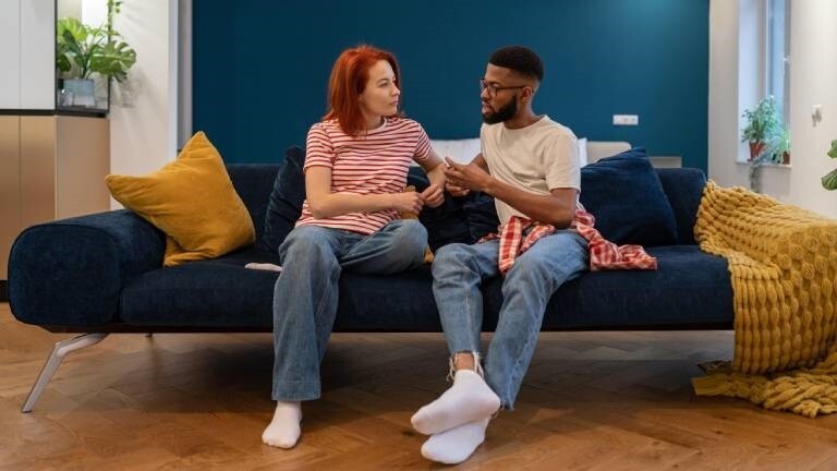 Eine Frau und ein Mann sitzen auf dem Sofa und unterhalten sich