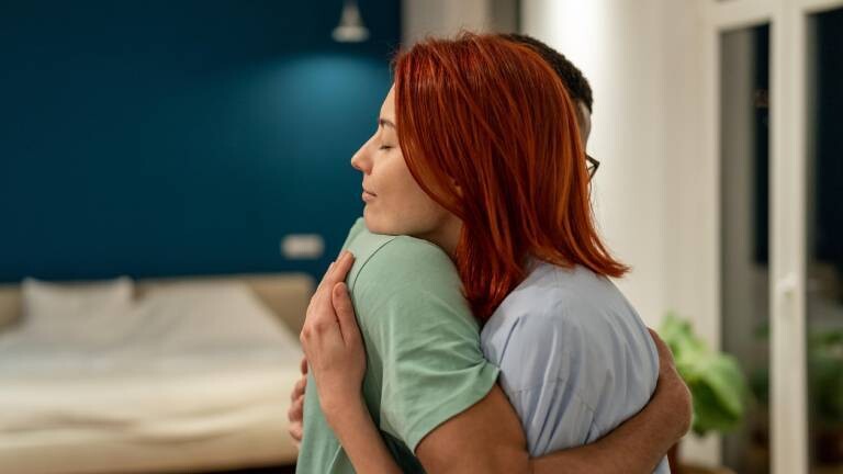 Zwei Personen umarmen sich im Schlafzimmer