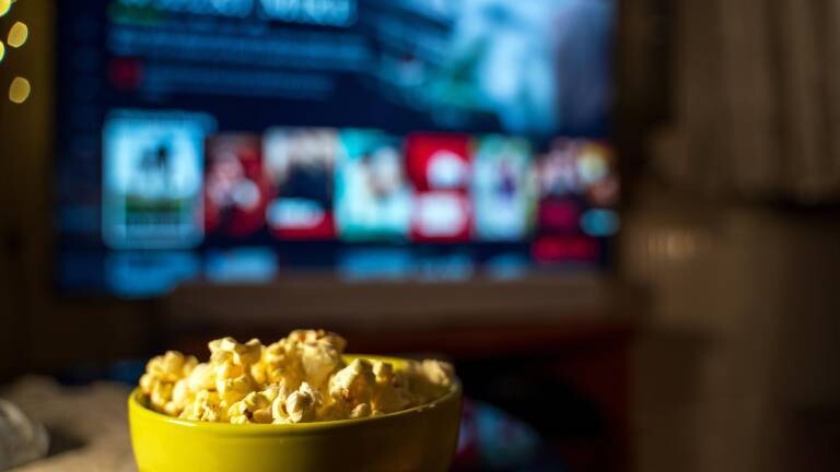 Eine Schale Popcorn vor einem Screen, auf dem gestreamt wird.