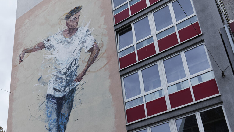 Mural eines jungen Mannes auf einer Häuserwand