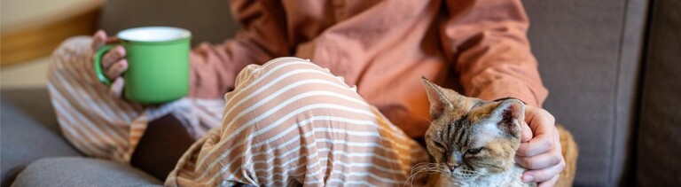 Eine Frau sitzt auf dem Sofa und streichelt eine Katze