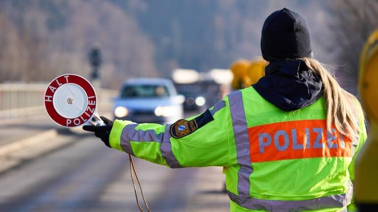 Polizistin stoppt Autoverkehr mit einer Polizeikelle am Grenzübergang