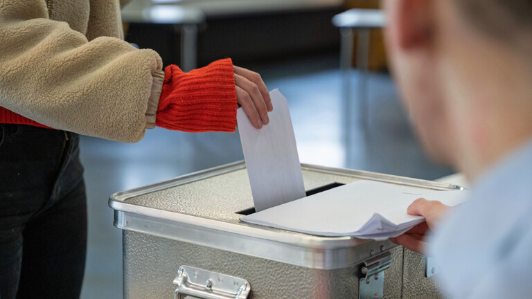 Eine Frau steckt ihren Stimmzettel für die Bundestagswahl in einem Wahllokal in eine Wahlurne.