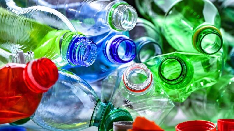 Bunte Plastikflaschen liegen mit der Öffnung zur Kamera durcheinander. Die Deckel sind alle abgeschraubt.