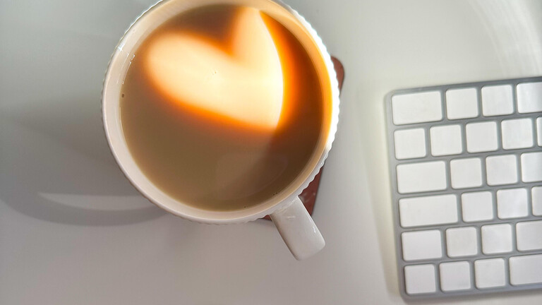 Eine Tasse Kaffee mit Herz auf einem Schreibtisch