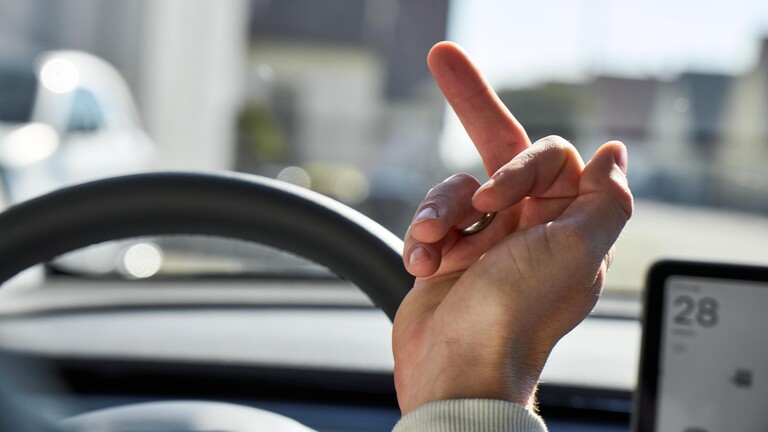 Autofahrer zeigt den Mittelfinger.