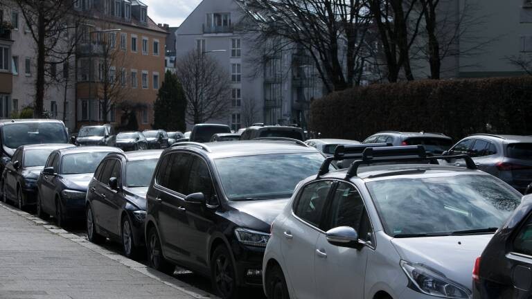 In einer Straße stehen dicht geparkt an beiden Straßenseiten sehr viele Autos.