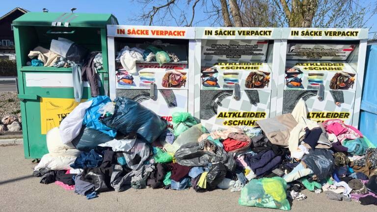 Mehrere überfüllte Altkleidercontainer.