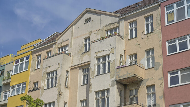Ein verfallenes Haus neben zwei renovierten Häusern