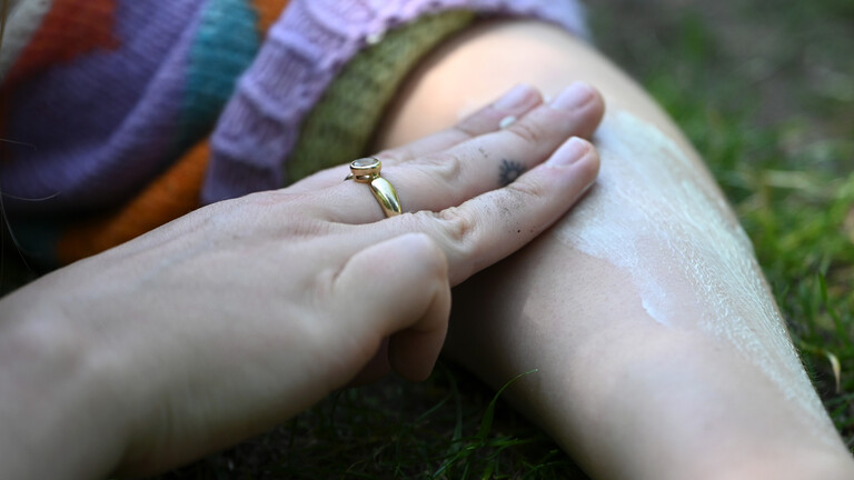 Eine Frau cremt ihren Arm mit Sonnencreme ein.