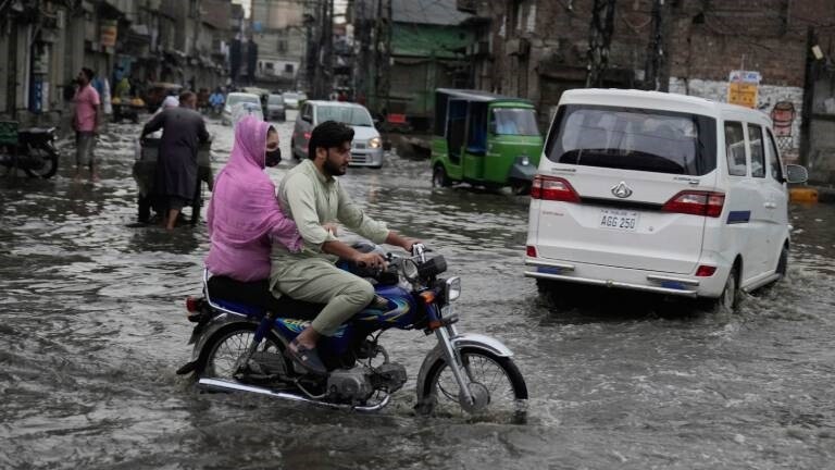 Menschen sind auf überfluteten Straßen in Lahore in Pakistan unterwegs